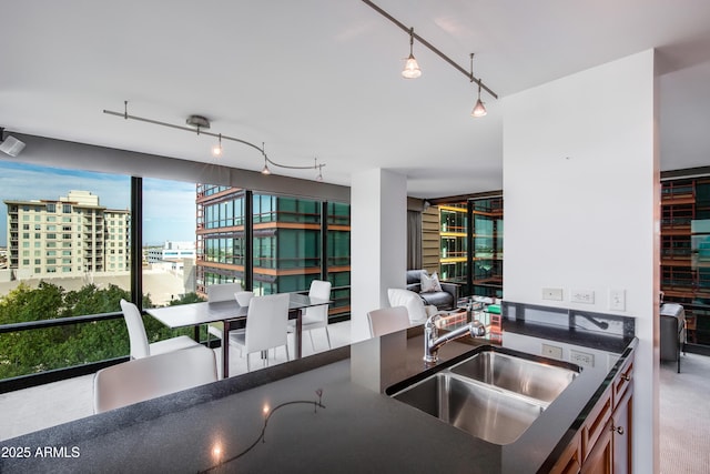 kitchen with dark countertops, open floor plan, rail lighting, a view of city, and a sink