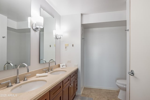 bathroom featuring baseboards, a sink, toilet, and double vanity