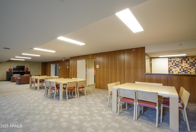 dining area with visible vents and wood walls