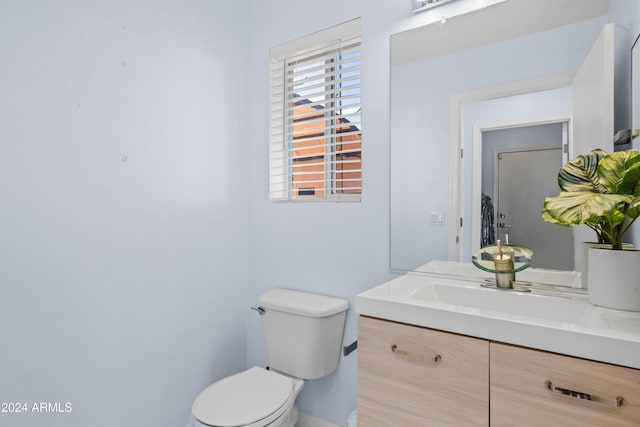 bathroom featuring toilet, vanity, and baseboards