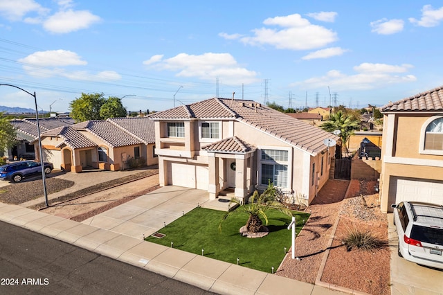 mediterranean / spanish-style home with stucco siding, driveway, an attached garage, a tile roof, and a front yard