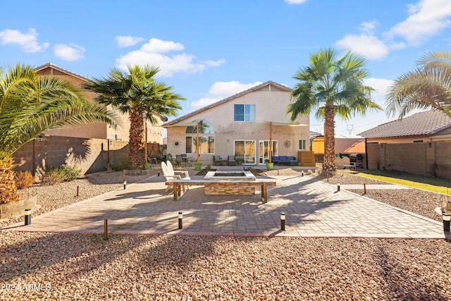 back of house featuring a patio, a fenced backyard, stucco siding, and a fire pit