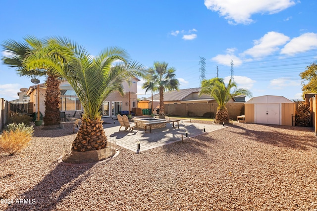 fenced backyard with a storage unit, a patio area, an outdoor fire pit, and an outbuilding