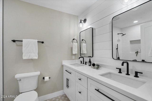 bathroom with toilet, vanity, and a tile shower