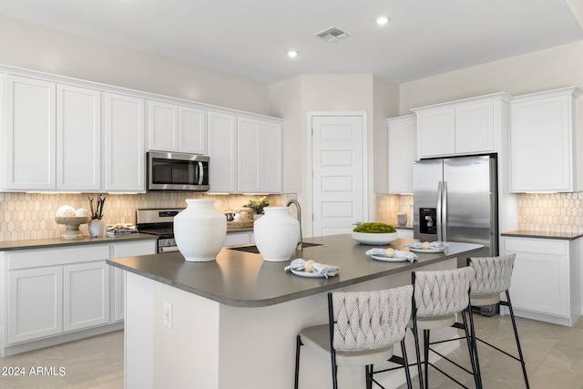 kitchen featuring a kitchen island with sink, white cabinets, and appliances with stainless steel finishes