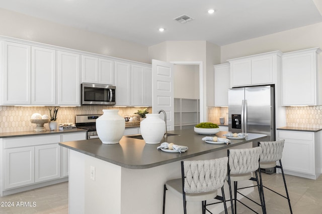 kitchen with stainless steel appliances, a kitchen island with sink, and white cabinets