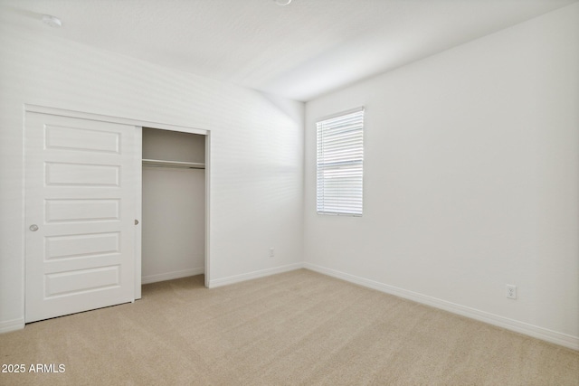 unfurnished bedroom with light colored carpet and a closet