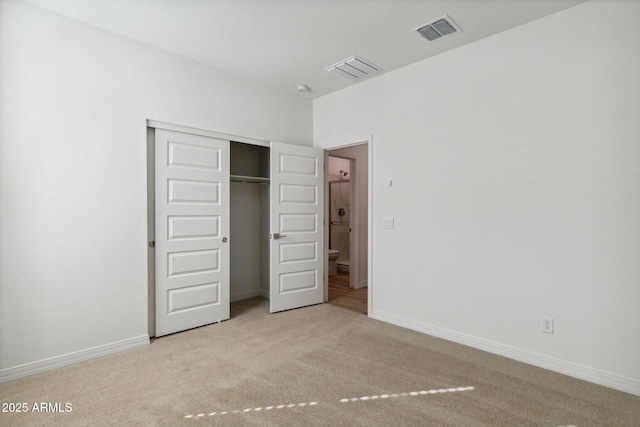 unfurnished bedroom with light colored carpet and a closet