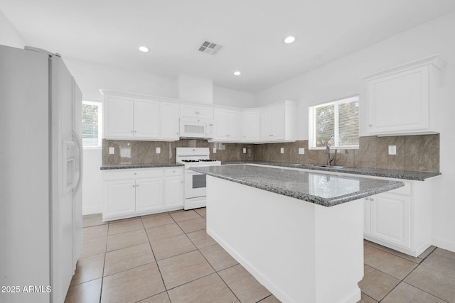 kitchen with white appliances, white cabinets, a sink, and light tile patterned flooring