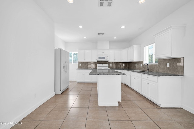 kitchen with white appliances, tasteful backsplash, light tile patterned floors, visible vents, and a center island