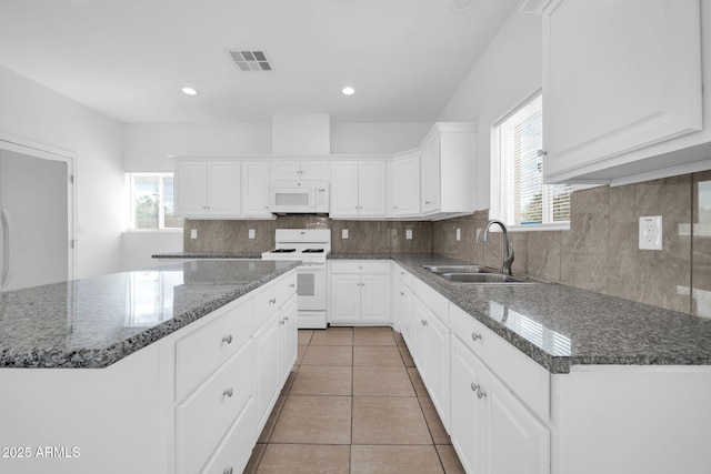 kitchen featuring white appliances, tasteful backsplash, visible vents, white cabinets, and a sink