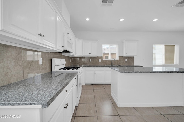 kitchen featuring backsplash, white gas range, a sink, and visible vents