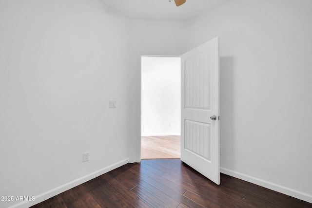 spare room featuring dark wood-style floors, ceiling fan, and baseboards