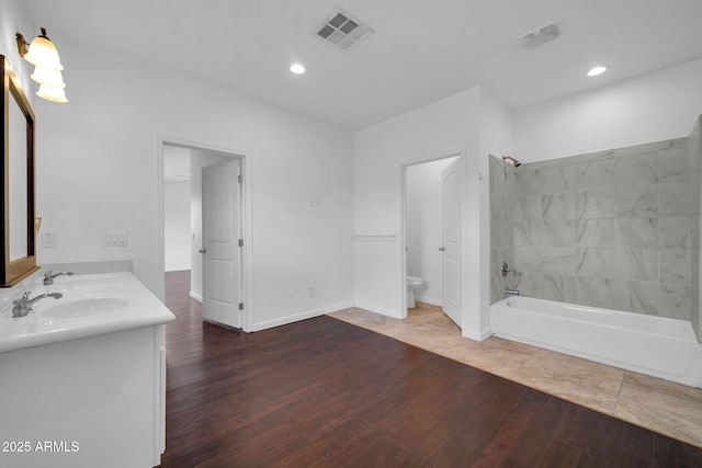 bathroom with shower / bath combination, double vanity, visible vents, toilet, and hardwood / wood-style floors