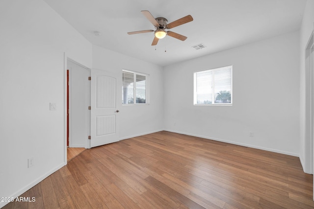 spare room featuring a ceiling fan, visible vents, baseboards, and hardwood / wood-style flooring