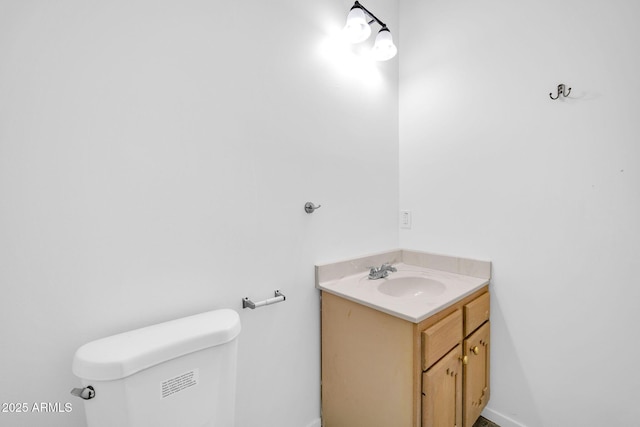 half bathroom with toilet, vanity, and baseboards