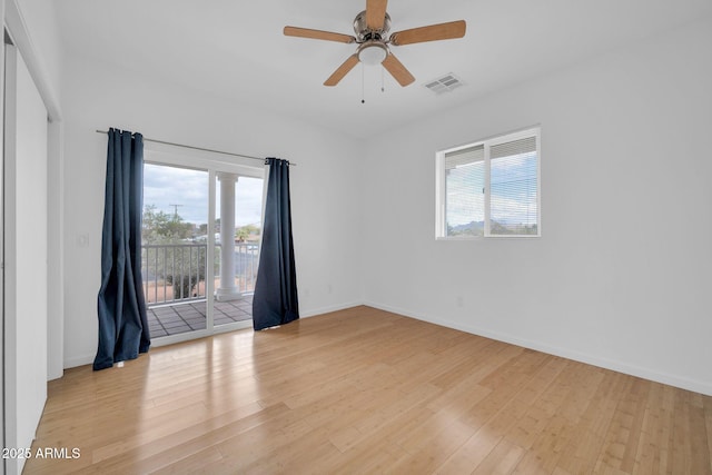 spare room featuring light wood finished floors, a ceiling fan, visible vents, and baseboards