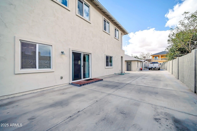 rear view of property with a patio area, fence, and stucco siding