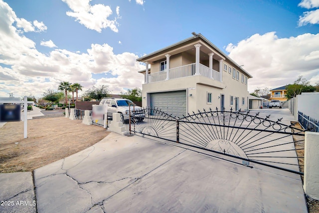 view of front of home with concrete driveway, a fenced front yard, an attached garage, a gate, and stucco siding