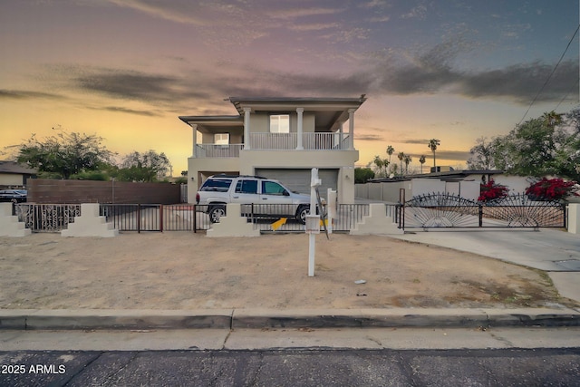 view of front of property featuring a garage, a balcony, a fenced front yard, and stucco siding