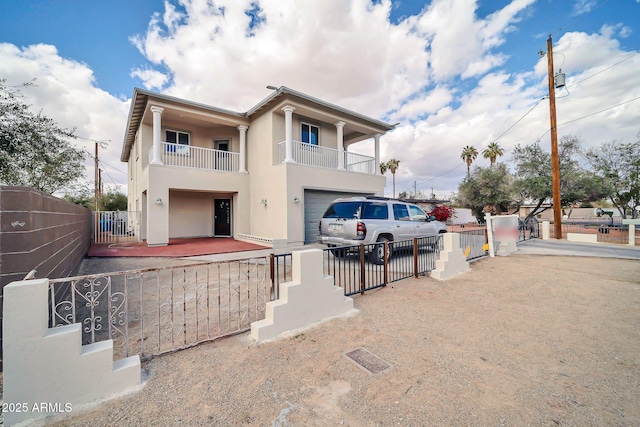 view of front of home with a fenced front yard, stucco siding, a balcony, a garage, and driveway