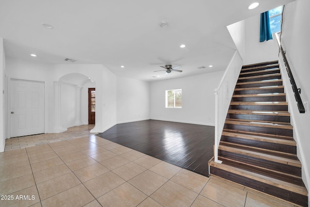 unfurnished living room featuring tile patterned flooring, stairs, arched walkways, and recessed lighting