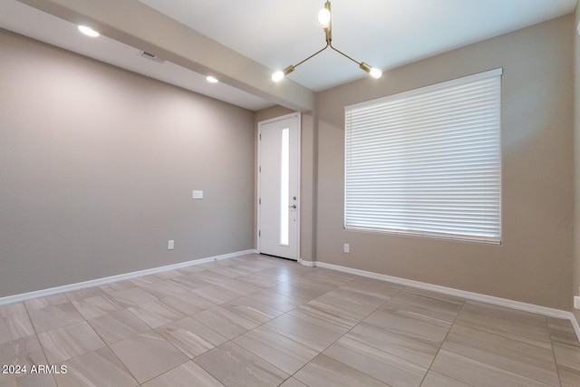 unfurnished room featuring an inviting chandelier