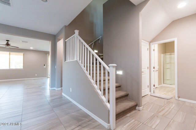 staircase featuring lofted ceiling and ceiling fan