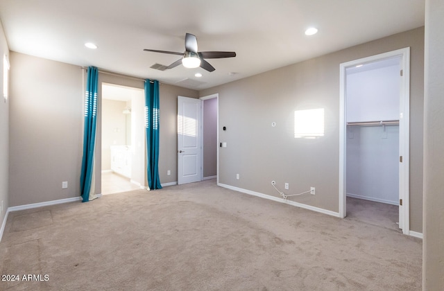 unfurnished bedroom with ceiling fan, light colored carpet, a closet, and a walk in closet