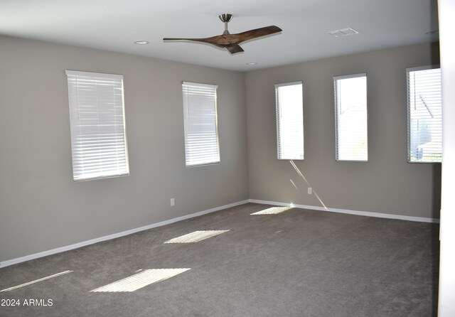 unfurnished room with dark carpet and ceiling fan