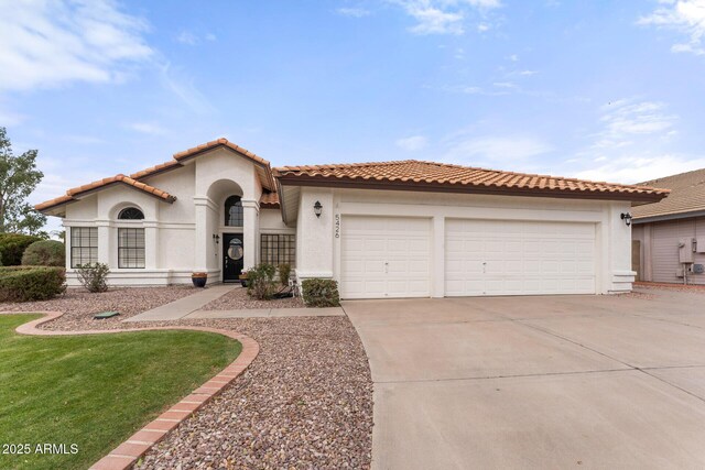 mediterranean / spanish-style house featuring stucco siding, driveway, a tile roof, a front yard, and an attached garage