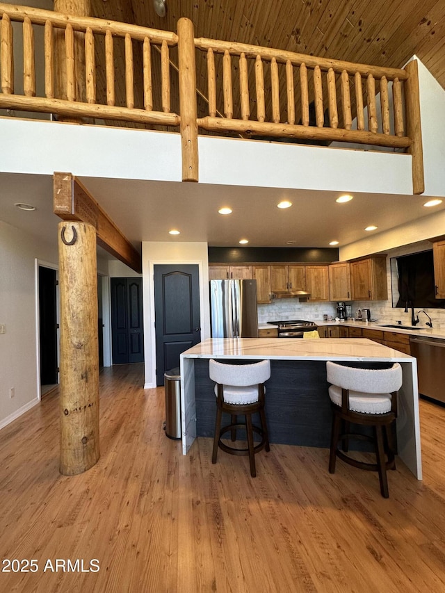 kitchen with brown cabinetry, light wood-style flooring, stainless steel appliances, and light countertops