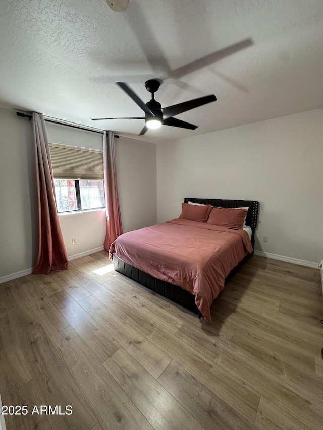 unfurnished bedroom with ceiling fan, wood finished floors, baseboards, and a textured ceiling