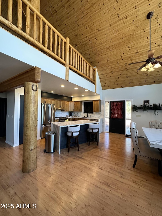 kitchen with brown cabinetry, freestanding refrigerator, light countertops, light wood-style floors, and wooden ceiling