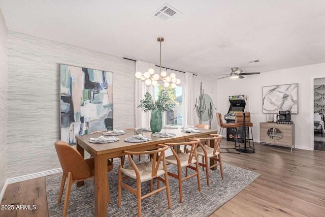 dining area featuring ceiling fan with notable chandelier and hardwood / wood-style floors