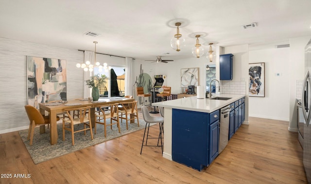 kitchen with blue cabinets, sink, pendant lighting, and kitchen peninsula