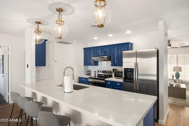 kitchen featuring blue cabinets, sink, backsplash, hanging light fixtures, and stainless steel appliances