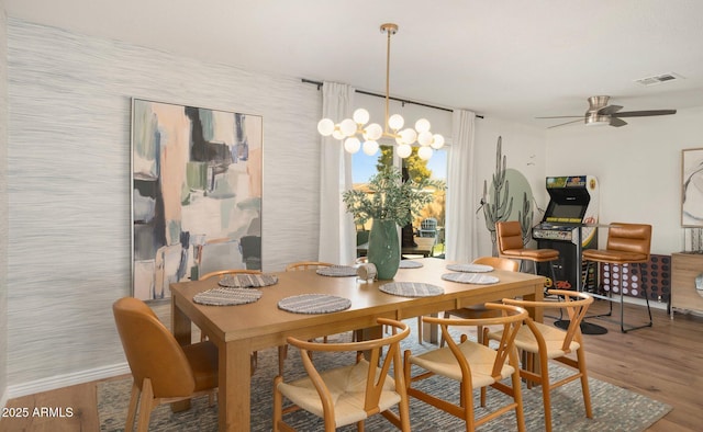 dining space featuring ceiling fan with notable chandelier and hardwood / wood-style floors