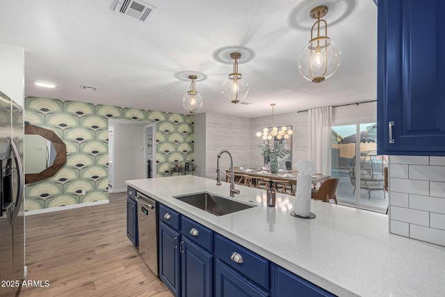 kitchen with sink, hanging light fixtures, dishwasher, and blue cabinets