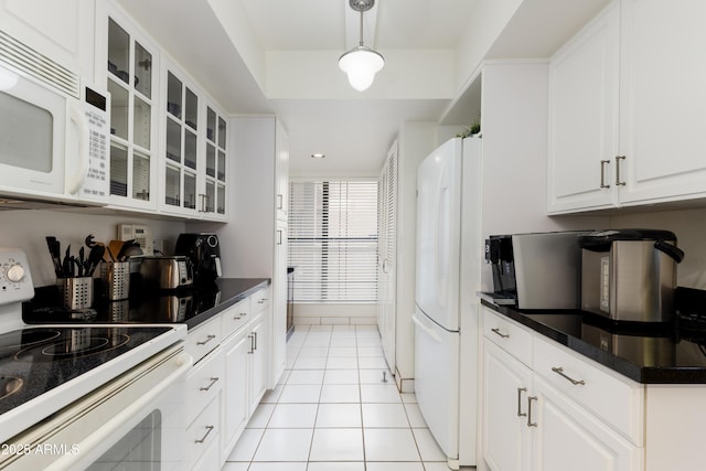 kitchen with dark countertops, white appliances, white cabinetry, and light tile patterned floors