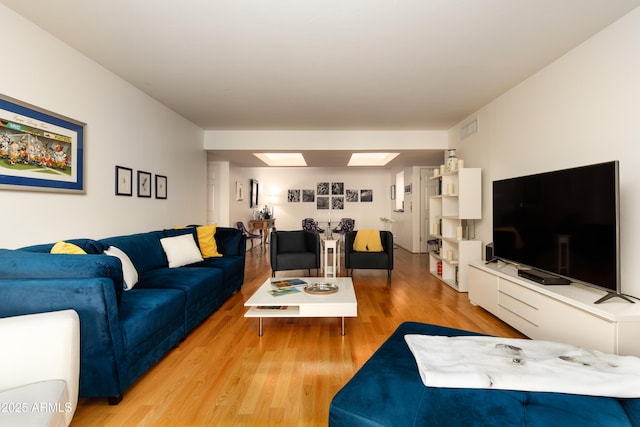 living area featuring a skylight, visible vents, and wood finished floors