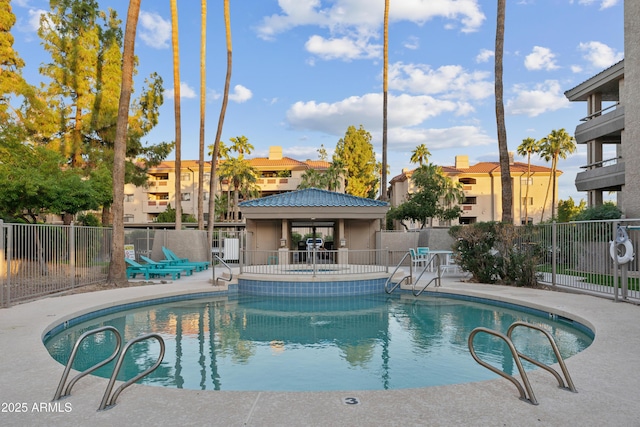 community pool with a patio area and fence