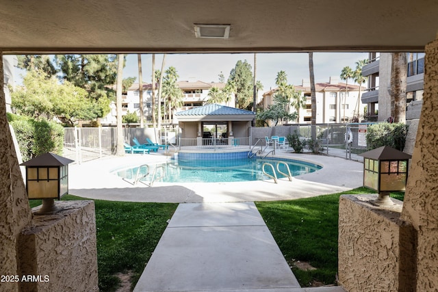 community pool with a patio area and fence