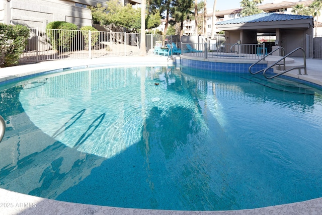 community pool with a patio area and fence