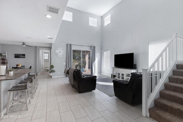 living room with ceiling fan, a healthy amount of sunlight, and a high ceiling