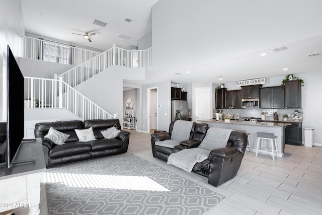 living room with ceiling fan, a towering ceiling, and light tile patterned floors