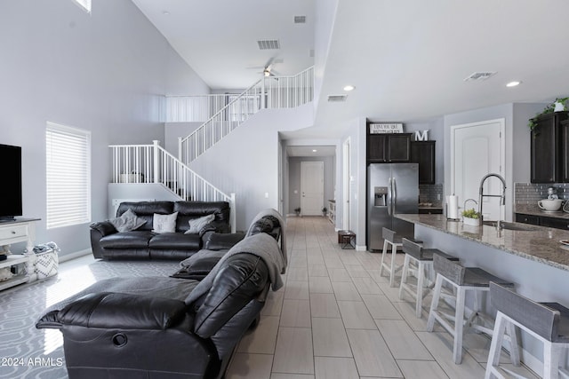 living room with a high ceiling, ceiling fan, and sink