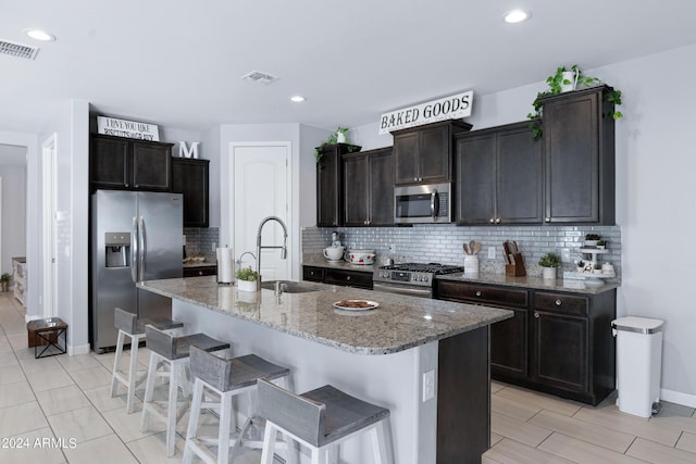 kitchen with appliances with stainless steel finishes, tasteful backsplash, a kitchen island with sink, and sink