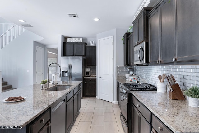 kitchen featuring light stone countertops, appliances with stainless steel finishes, tasteful backsplash, sink, and light tile patterned flooring