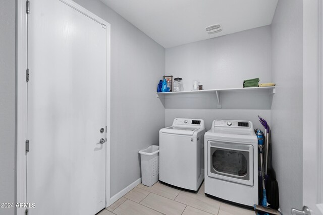 clothes washing area with washing machine and clothes dryer and light tile patterned floors